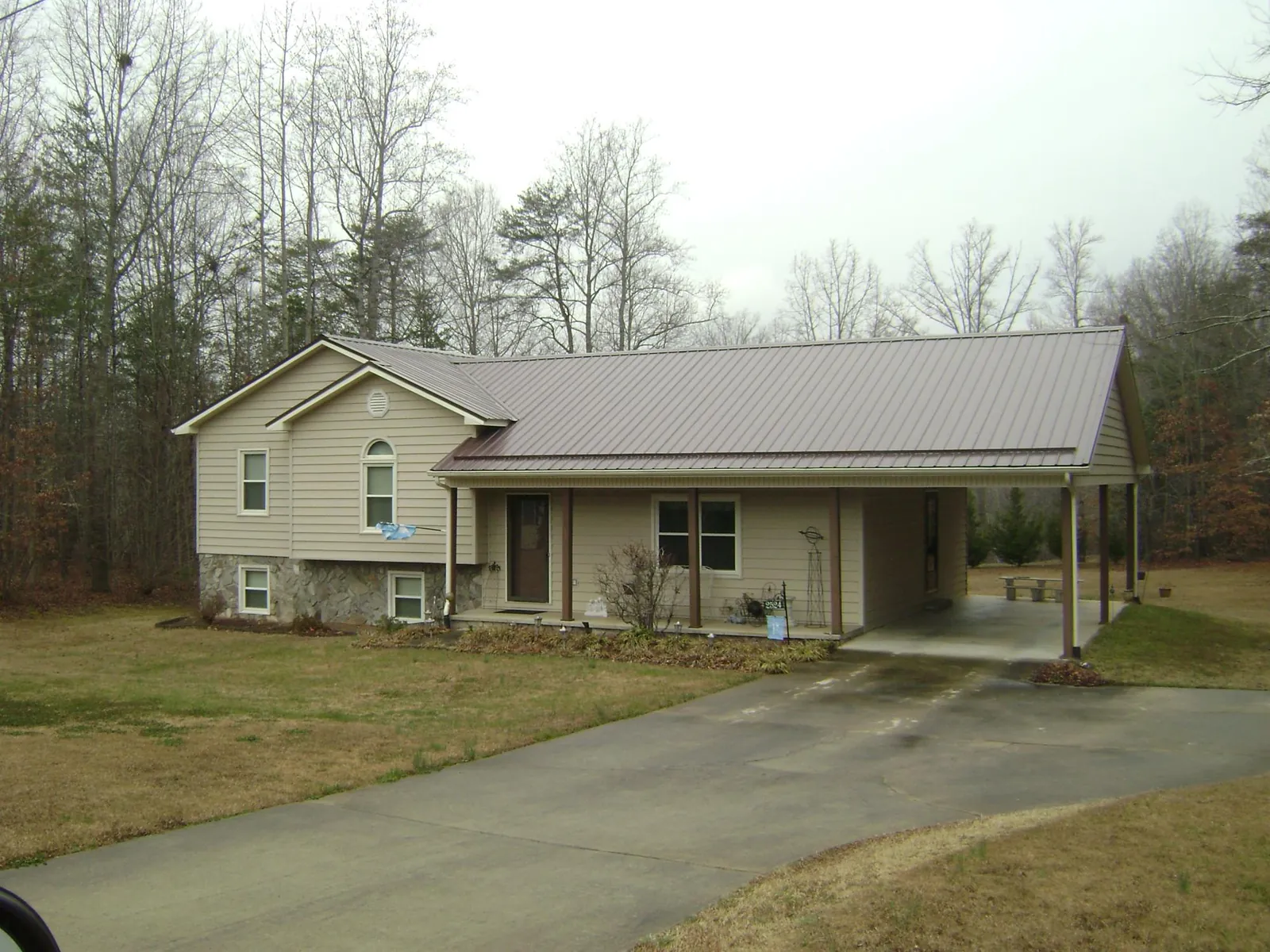 Brown metal roof on a tan split level home with an attached carport in Evansville